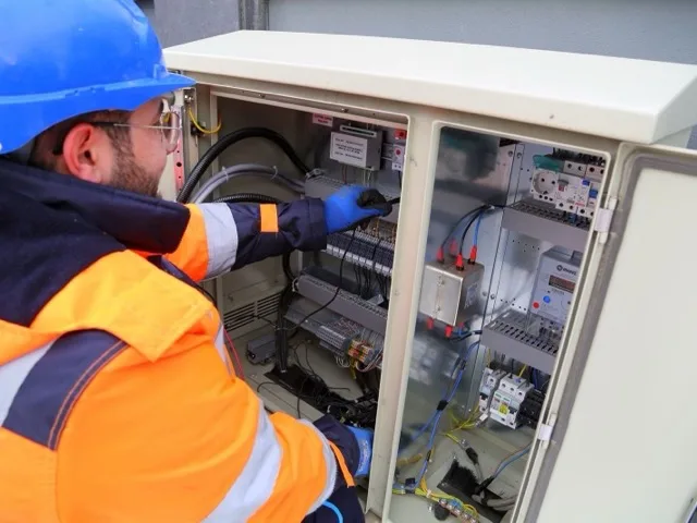 Szerelő teljes egyéni védőfelszerelésben energiatároló konténernél